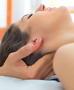 Therapist massaging the neck of woman In the studio